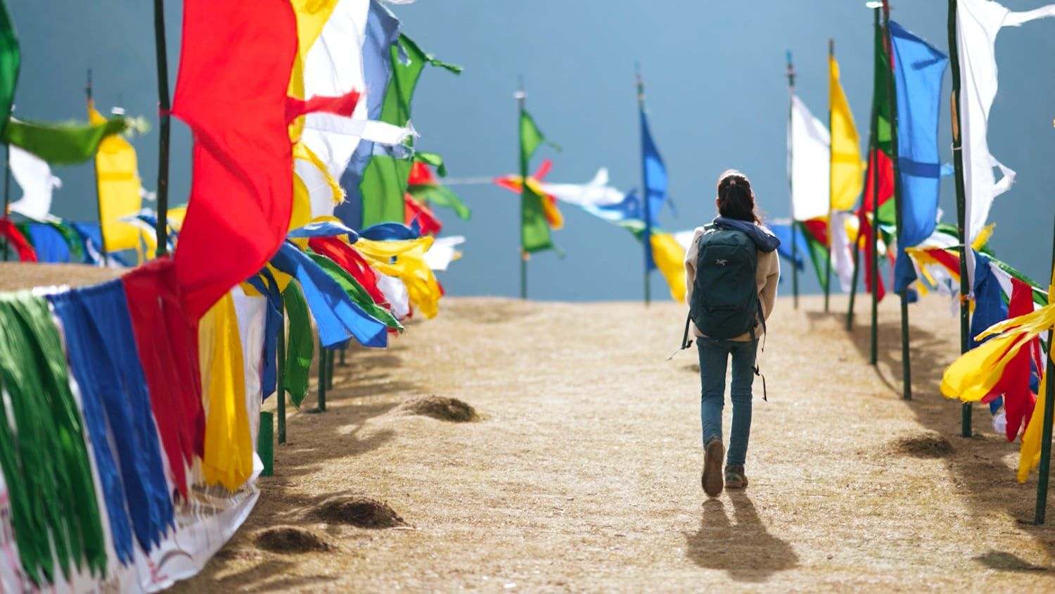 Hillary O’Sullivan walking between prayer flags in Laya, Bhutan, a still from The Girl and Her Piano