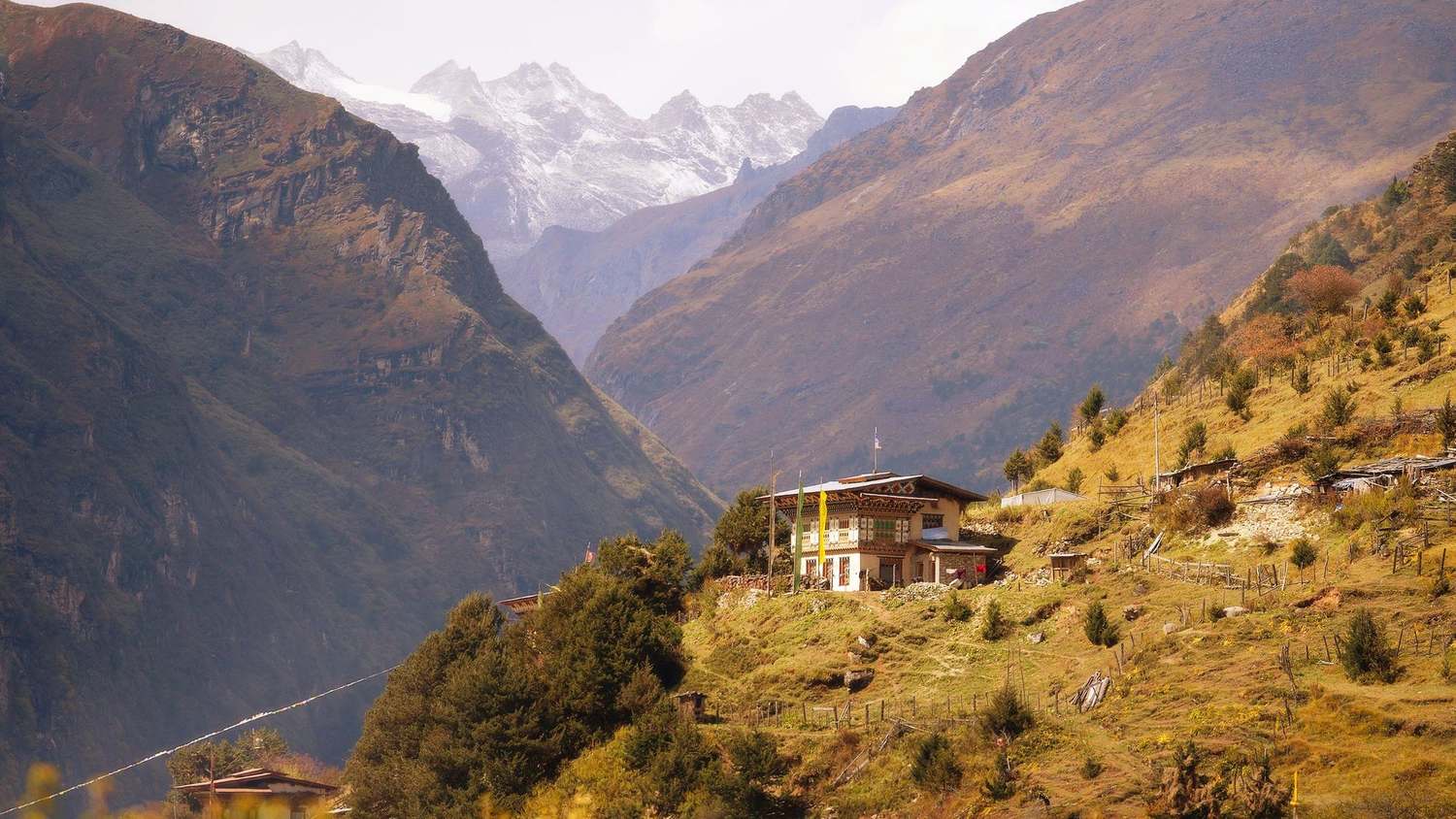 A farmhouse on the slope above Laya, Bhutan, with a glacier in the valley beyond