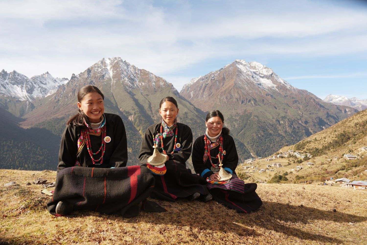 Women of Laya in traditional dress beside a yak, below the snow peaks of the Bhutanese Himalaya