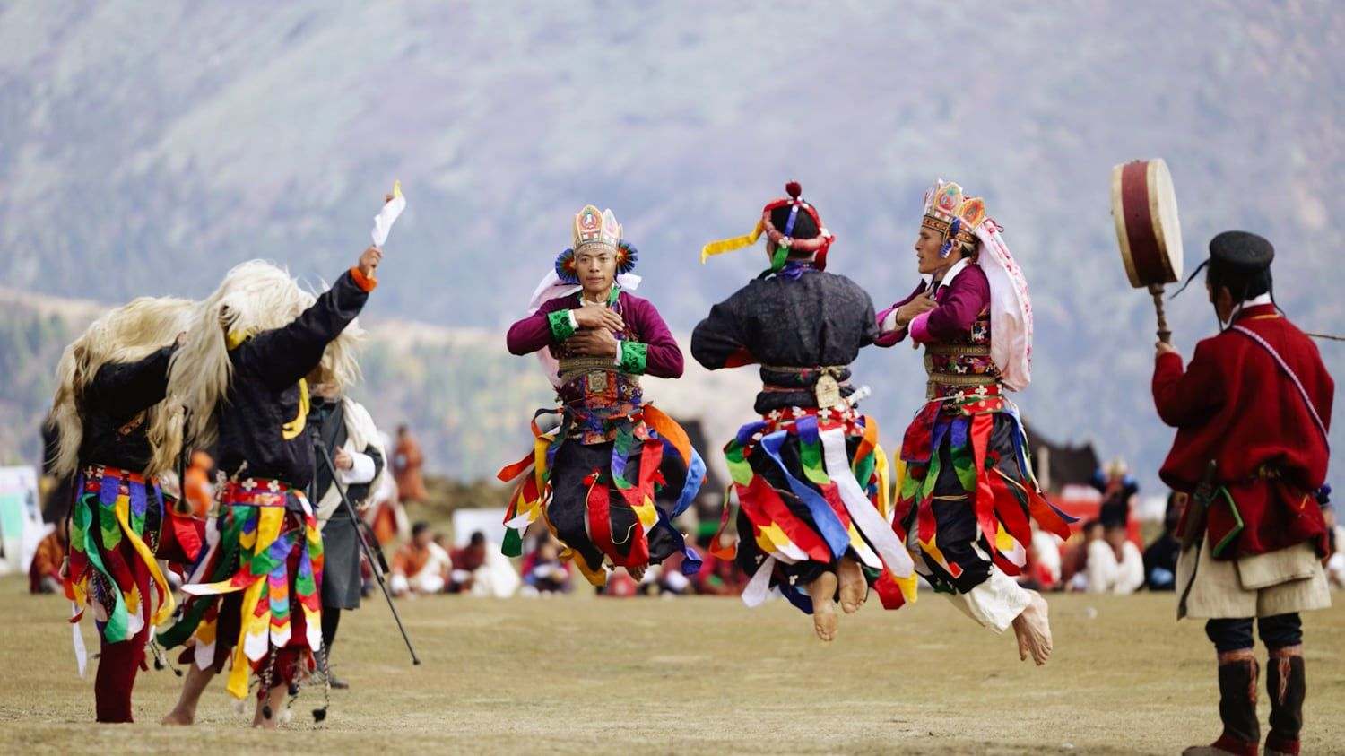 Dancers mid-leap in traditional dress at the Royal Highland Festival in Laya, Bhutan