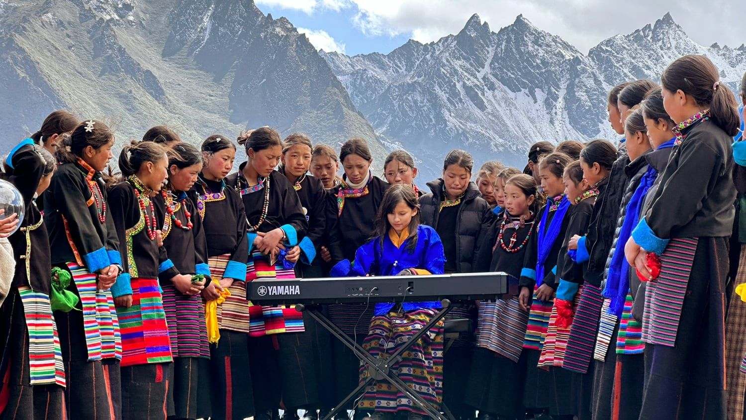 Hillary O’Sullivan accompanying the children’s choir of Laya at the Royal Highland Festival, the Himalaya behind them, a scene in The Girl and Her Piano