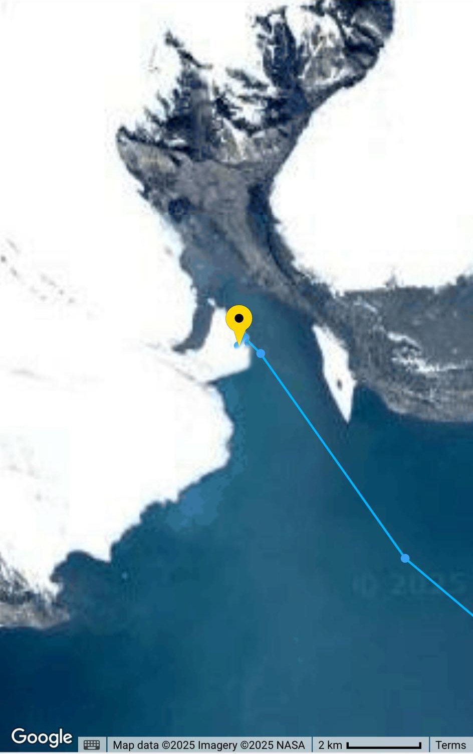 A satellite map of a Svalbard coast with the ship’s track drawn as a blue line that ends inside the white of a glacier.